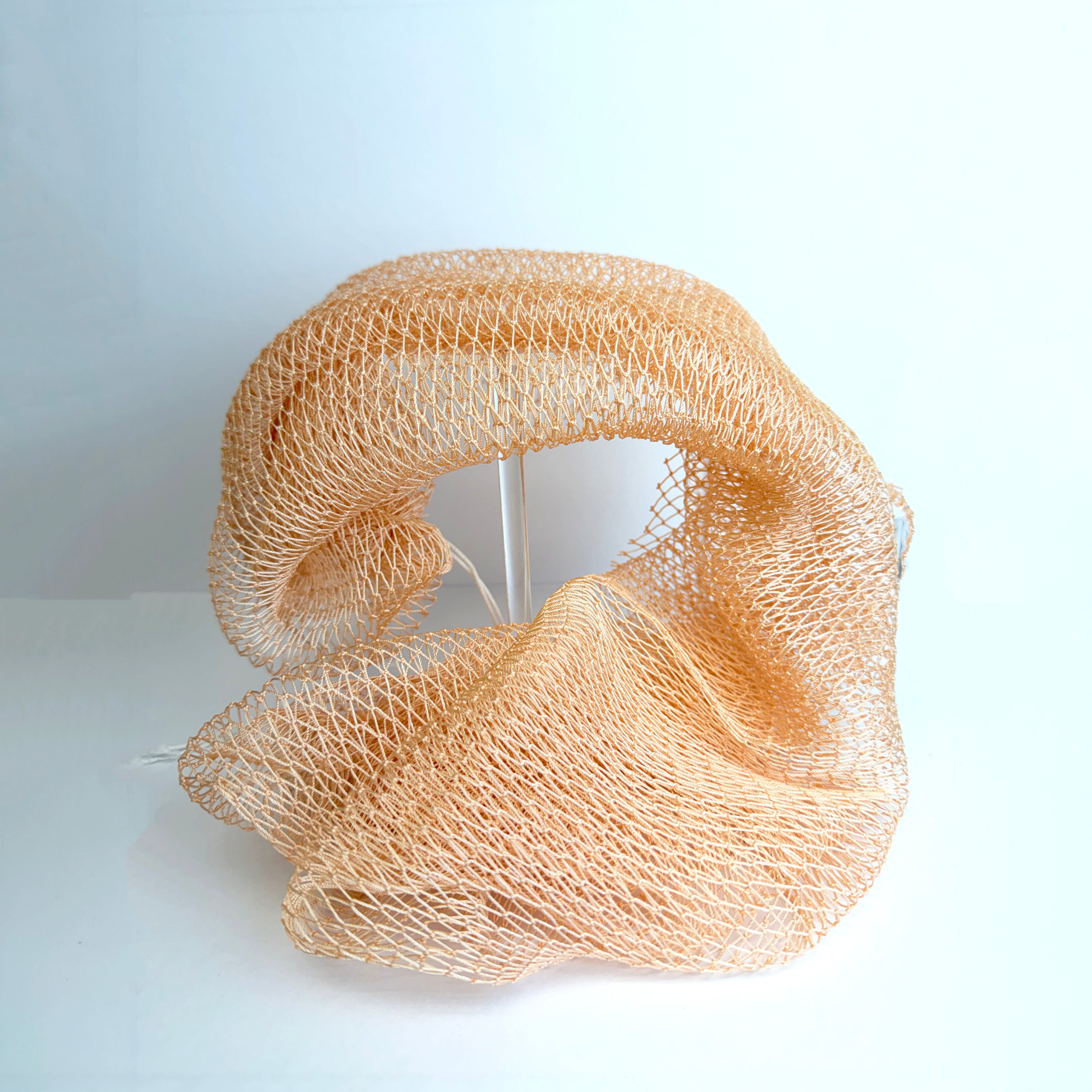 Blush orange net sponge draped over a stand 